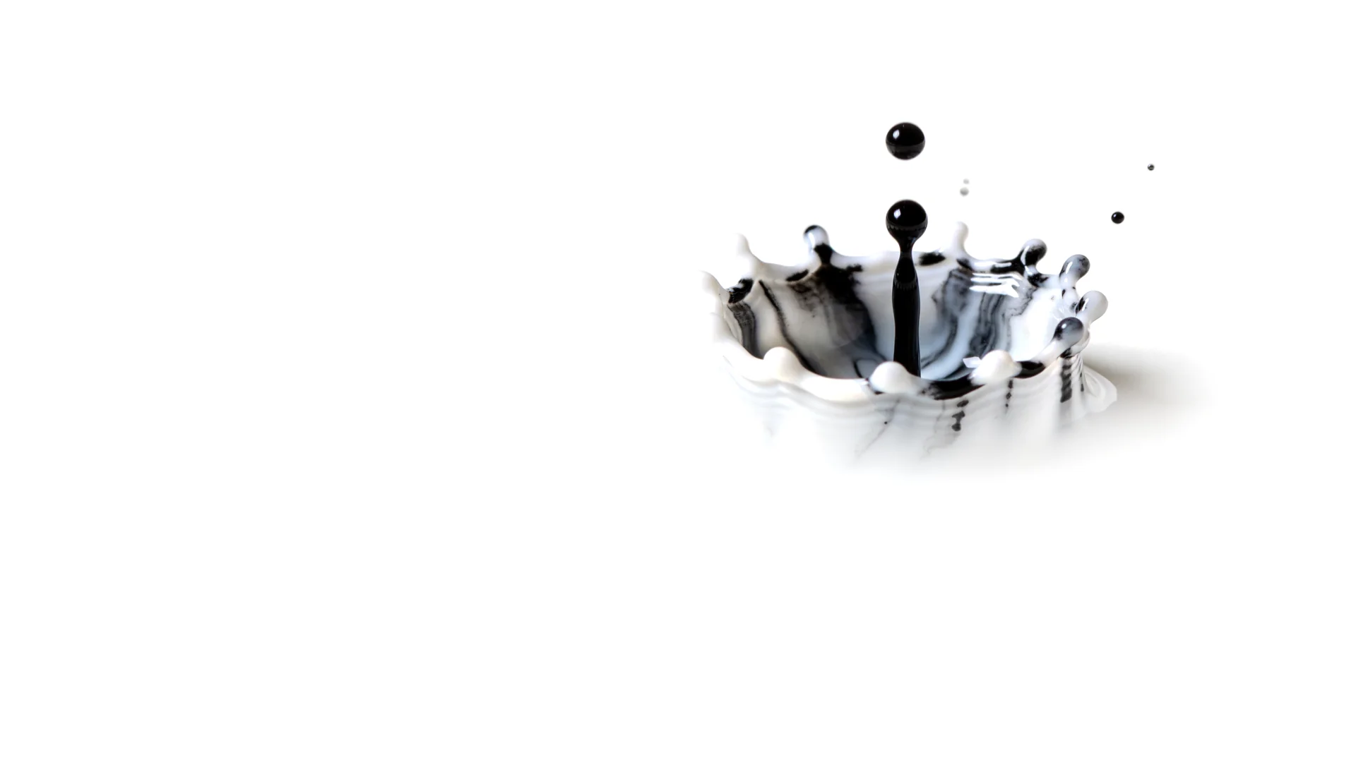 A drop of ink striking milk, held at the instant of the splash.